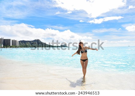 Happy beach woman in bikini joyful and free on Waikiki, Oahu, Hawaii, USA. Girl on travel vacation holidays having fun on Hawaiian Waikiki beach with Diamond Head mountain. Asian Caucasian model.