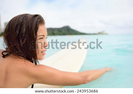 Surfer girl surfing paddeling on surfboard. Female surf bikini woman living healthy active water sports lifestyle on Hawaiian beach. Asian Caucasian model on Waikiki Beach, Oahu, Hawaii.