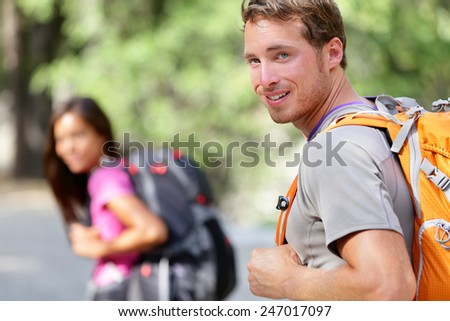 Hiking people. Young couple of hikers walking. Caucasian man smiling happy in foreground with young woman in background during summer trip in Yosemite National Park, California, USA.