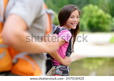 Hiker. Woman hiking smiling happy on trek with backpack during summer outdoors activity. Multiethnic Asian Caucasian female model walking with a group on a day excursion trip hike in the forest.
