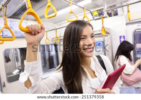 Subway commuter woman on Japanese public transport in Tokyo, Japan. Tourist using Japan\'s capital city metro system to commute. Portrait of happy asian lady holding handhold inside the wagon.