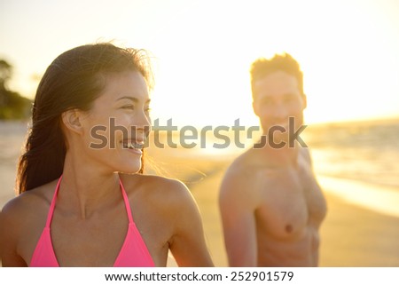 Joyful young mixed race couple on beach sunset enjoying summer vacation holiday travel. Beautiful smiling Asian woman, young pretty Caucasian male. Hawaii.
