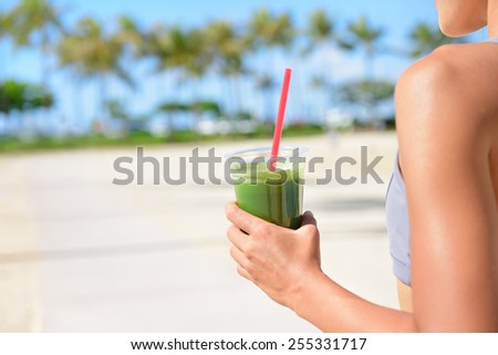 Vegetable green detox cleanse smoothie - Woman drinking after fitness running workout on summer day. Girl drinking green juice or smoothie in fitness and healthy lifestyle concept.