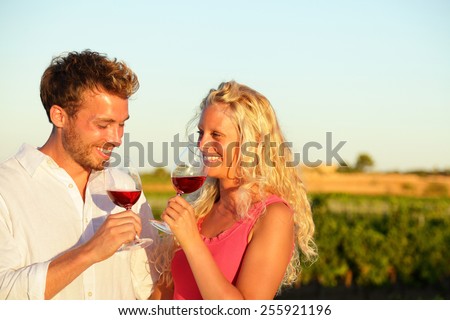 Drinking red wine couple in love. Happy people drinking rose wine alcohol laughing in summer vineyard.