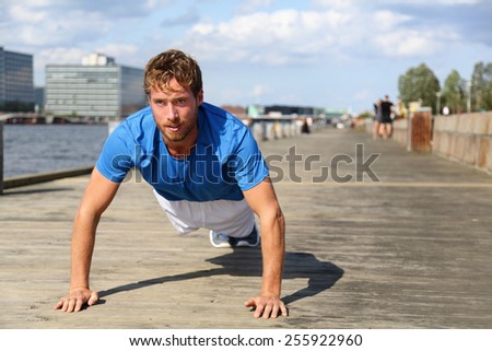 Sport fitness man push-ups. Male athlete exercising push up outside in urban city boardwalk. Fit male fitness model in crossfit exercise outdoors. Healthy lifestyle in Bryggen, Copenhagen, Denmark