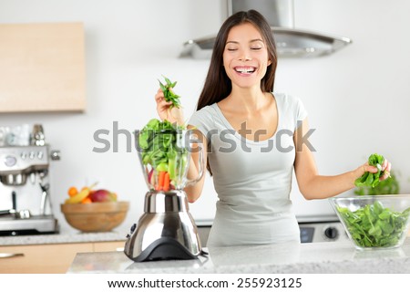 Green smoothie woman making vegetable smoothies with blender home in kitchen. Healthy eating lifestyle concept portrait of beautiful young woman preparing drink with spinach, carrots, celery etc.