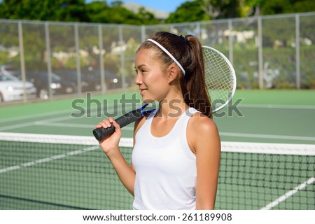 Female tennis player portrait with tennis racket outdoors in tennis court in summer. Fit female athlete playing tennis living healthy active sport and fitness lifestyle. Mixed race Asian Caucasian.