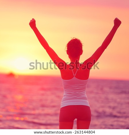 Life achievement - happy woman arms up in success. Back view of female silhouette proud of reaching her health goal arms raised looking at ocean and sunset. Happiness winning goal concept.