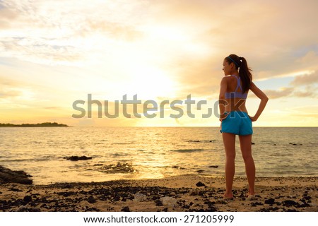 Aspirations - woman looking away with inspiration. Fitness woman after run in sunset on beach looking at ocean feeling peaceful and serene relaxing during summer. Mindfulness concept.