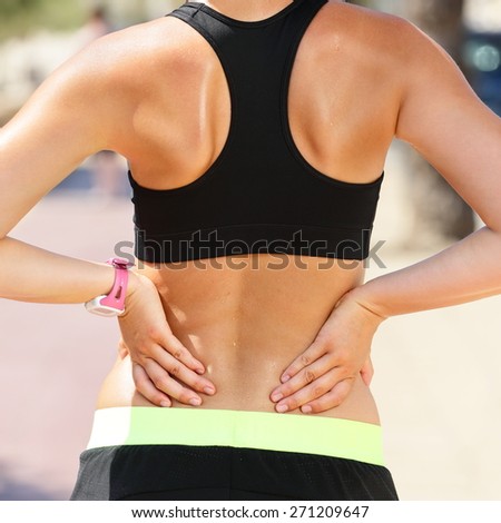 Sports injury - Lower back pain woman holding body touching painful waist muscles showing smartwatch on wrist..