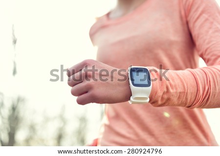 Heart rate monitor smart watch for sport. Athlete wearing heart rate monitor. Runner using sports smartwatch on running workout outside. Female athlete tracking activities using wearable technology.