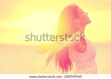 Happiness - Free happy woman enjoying sunset. Beautiful woman in white dress embracing the golden sunshine glow of sunset with arms outspread and face raised in sky enjoying peace, serenity in nature