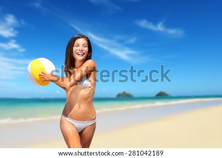 Beach woman playing with ball having fun laughing happy on Lanikai Beach, Oahu, Hawaii. Young mixed race asian caucasian woman playing ball in sea waves - smiling, enjoying the sun. Big Island, Hawaii