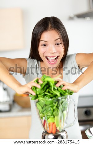 Vegetable smoothie woman making green smoothies with blender home in kitchen. Funny healthy raw eating lifestyle concept portrait of beautiful young woman preparing drink with spinach, carrots, celery