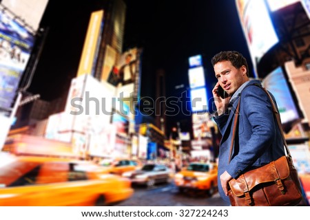 Young urban professional business man talking on smart phone onTimes Square, Manhattan, New York City. Young hip male businessman in casual suit in at night outdoors.