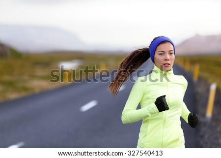 Female runner running in warm clothing for winter and autumn outside. Woman runner training in cold weather living healthy active lifestyle.
