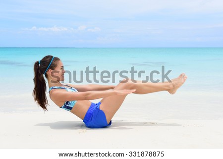 Fitness woman on beach with toned in shape body body doing v-up crunch ab toning exercise workout as part of an active lifestyle for weight loss.