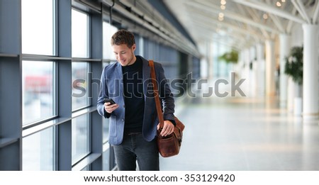 Man on smart phone - young businessman in airport. Casual urban professional business man using smartphone smiling happy inside office building. Handsome man wearing suit jacket indoors.