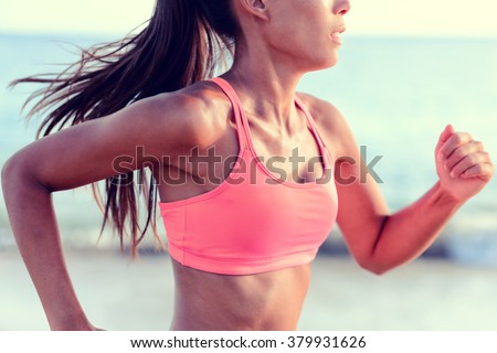 Cardio running workout - Upper body closeup crop of unrecognizable woman runner in fast motion showing pink sports bra activewear clothing in ocean beach nature background.