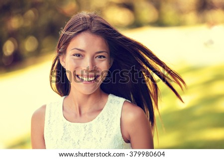 Confident young Asian Chinese beauty woman smiling. Beautiful portrait of healthy female adult in sunny summer grass park background for spring, summertime or pollen allergy season concept.