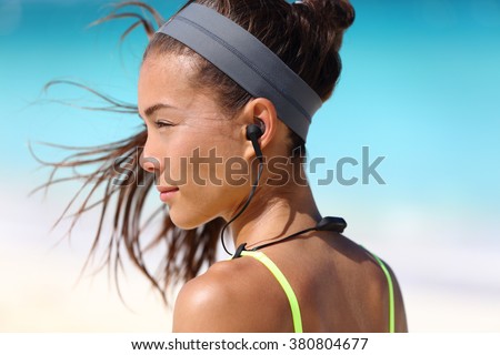 Fitness girl with sport in-ear wireless headphones. Asian female athlete woman runner wearing Bluetooth earphones with wing tip design for sports activities. Portrait closeup.