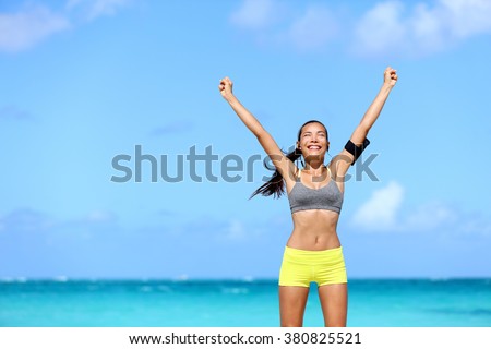 Happy success woman - achievement of fitness goals. Winning female athlete with arms up successful of achieving her workout or diet goal. Healthy Asian runner girl living a healthy lifestyle.