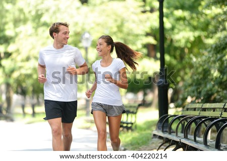 Runners jogging together in New York City Central Park, USA. Healthy couple of new yorkers athletes friends running in summer sun working out a cardio exercise on Manhattan, United Sates of America.