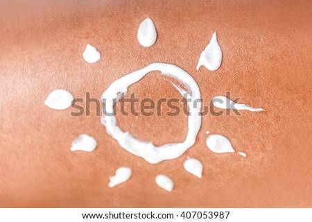 Sunscreen suntan lotion sun drawing in sunblock cream on tanned skin closeup. Female body crop of illustration painted on body Concept for skin cancer or sunburn uv rays protection.
