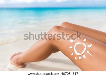 Sunscreen sun drawing lotion on suntan legs relaxing tanning on tropical beach holiday. Women lower body lying with sunblock cream in shape for skin cancer sunburn care concept.