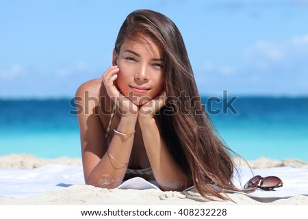 Beauty portrait of mixed race Asian Caucasian woman on beach. Young lady with perfect skin wearing bikini and jewelry - bracelet and necklace - relaxing on beach. Fashion model on vacation travel.