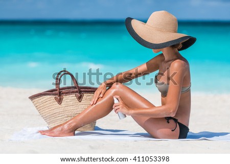 Girl oil spray tanning her legs protection from the sun\'s uv rays putting sunscreen lotion sunblock Unrecognizable girl with her beach essentials for a summer holiday - straw sun hat and tote bag.