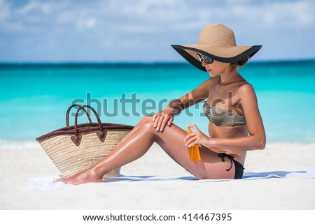 Beach accessories essentials for a summer holiday tropical vacation: sunglasses, straw hat, tote bag, towel, sunscreen. Sexy bikini woman applying sunblock sun protection lotion on Caribbean travel.