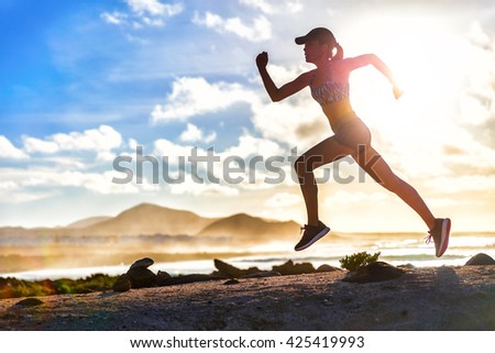 Athlete runner trail running on summer beach. Fit body silhouette of sports Woman in sportswear cap sprinting with energy and motion in outdoors nature training cardio with jogging workout exercise.