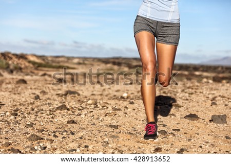 Summer trail running athlete runner legs lower body crop. Fitness woman jogging living an active lifestyle jogging on rocky path in mountain nature landscape. Shoes, knees, thighs weight loss concept.