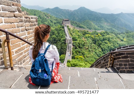 Great Wall of China. Tourist on Asia travel looking at Chinese landscape sitting relaxing on famous Chinese tourist destination and attraction in Badaling north of Beijing. Woman traveler on vacation.
