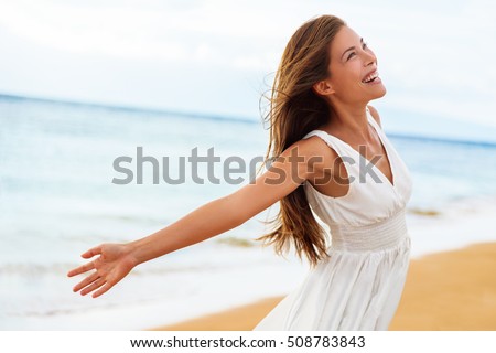 Free happy woman on beach enjoying nature. Natural beauty girl outdoor in freedom enjoyment concept. Mixed race Caucasian Asian girl posing on travel vacation holidays in dress.