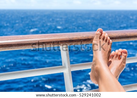 Relaxation on cruise ship travel holiday. Closeup of women feet up on balcony overlooking ocean view on caribbean vacation at sea. Barefoot woman sun tanning relaxing at outdoor spa.
