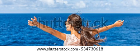 Happy freedom woman with open arms looking at blue sea horizon outdoors. Carefree person living a free life. Panorama horizontal banner crop for success and bliss concept.