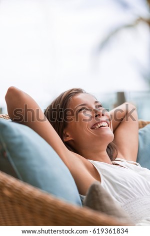 Home lifestyle woman relaxing enjoying luxury sofa patio furniture on outdoor patio living room or hotel. Happy lady lying down on comfortable pillows . Beautiful young Asian chinese girl.