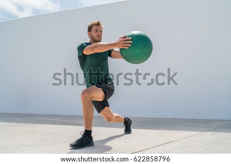 Working out man training legs and core ab workout doing lunge twist exercise with medicine ball weight. Gym athlete doing lunges and torso rotations for abs training.
