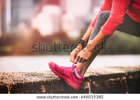 Runner woman getting ready to run tying running shoes laces. Healthy lifestyle jogging motivation closeup of feet or footwear.