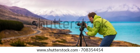 Travel photographer man taking nature video of mountain landscape at Peter's lookout, New Zealand Banner. Hiker tourist professional videographer on adventure vacation shooting slr camera on tripod.