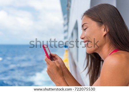 Cruise ship woman using mobile phone on travel vacation at ocean. Asian girl texting sms on wifi on tropical holidays. Internet on international seas concept. Tourist looking at her holiday pictures.