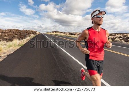 Runner fit athlete man running in triathlon suit training for Iron man on Hawaii. Fit male triathlete exercising endurance cardio on road.