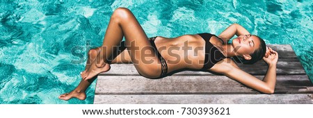 Luxury travel bikini girl vacation banner. Asian woman sun tan over idyllic ocean water in Bora Bora Tahiti, French Polynesia island. Panoramic horizontal crop of exotic holiday.