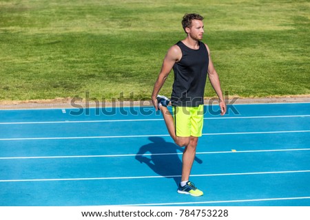 Runner athlete man doing warm-up stretching quads muscles doing leg workout before training on running tracks in stadium. Exercise and sports fitness jogger getting ready for competition.