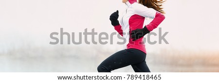 Winter fitness woman running in cold weather clothes wearing gloves and thermal pants, jacket jogging in white snow background landscape panorama banner.