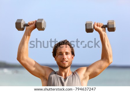 Fitness gym man lifting dumbbell weights. Male athlete with muscular arms with dumbbells overhead doing shoulder press training biceps. Athlete holding two free heavy weights.