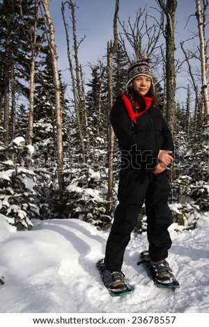 Young woman snowshoeing in pine forest near Baie Saint-Paul, Quebec, Canada