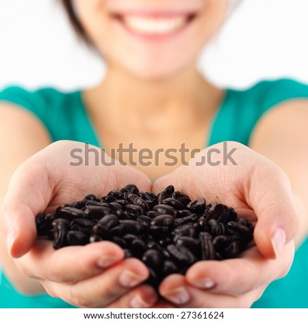 Attractive woman holding coffee beans. Shallow depth of field, focus on the middle of the beans. Isolated on white.